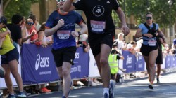 A picture of myself (Luc Shelton) running the final stretch of the ASICS London 10K. I am running alongside someone who is waving.